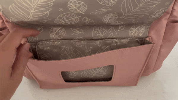 The front magnetic closure pocket of the TWELVElittle Peek-A-Boo Backpack holds a wipe pouch, but it can also be used as a regular pocket by moving the center magnetic snap divider.