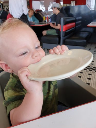 baby boy chewing on dish