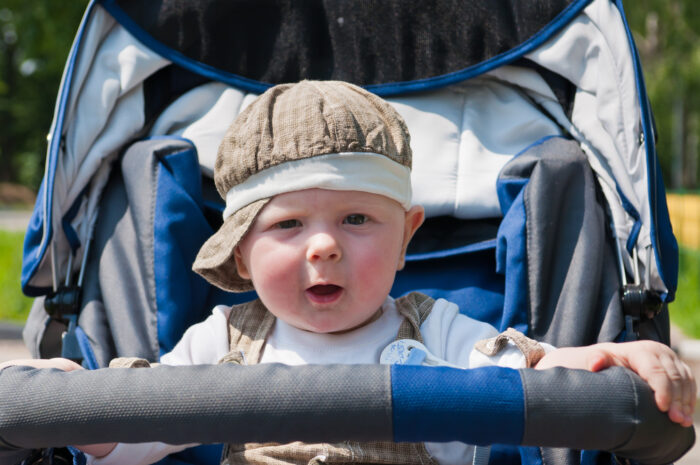 Adorable baby boy wearing a hat sitting in stroller