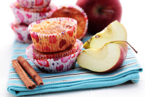 apple muffins next to apple slices and a cinnamon stick