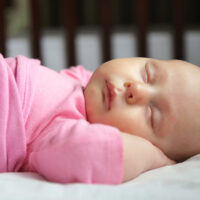 Newborn girl asleep in small crib