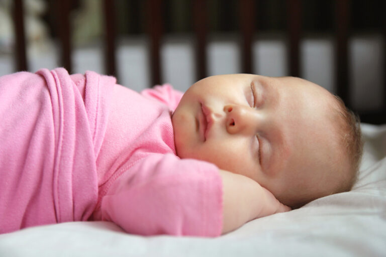 Newborn girl asleep in small crib