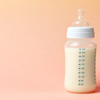 Baby Bottle on Table with Peach Background