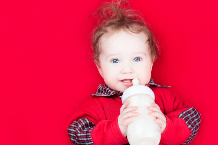 Baby Girl Drinking Warm Formula on Red Blanket