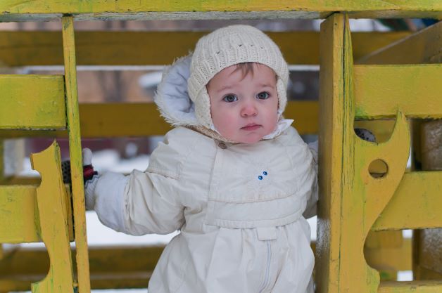 Baby girl playing at playground in cold and snow