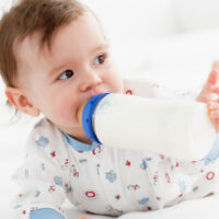 Cute baby sucking on bottle while on belly