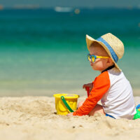 Baby on the beach in his sun hate