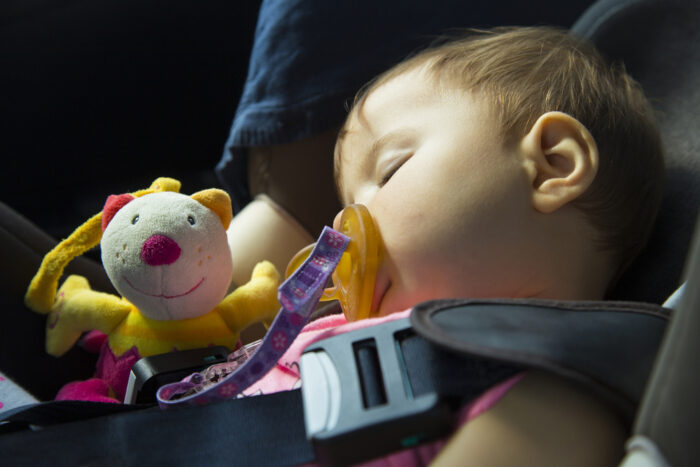 Baby girl safely asleep in car seat