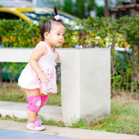 toddler on sidewalk wearing knee pads