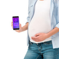 pregnant woman holding phone with baby registry app on a white background