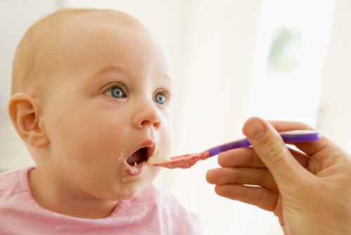 mother using baby spoon to feed pureed food to baby girl