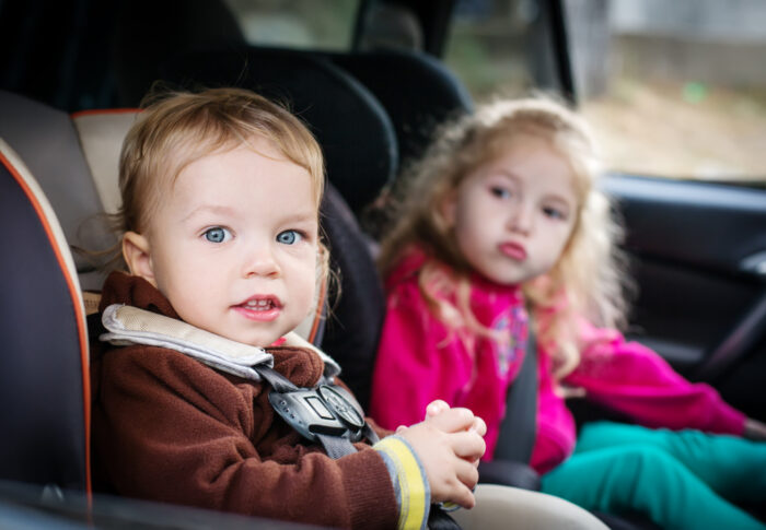 two toddlers sitting in car seats in vehicle