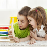 two small children playing with abacus math toy and having fun