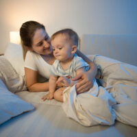 mom and baby sitting in bed at night