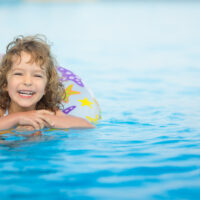 child swimming on pool float toy in water