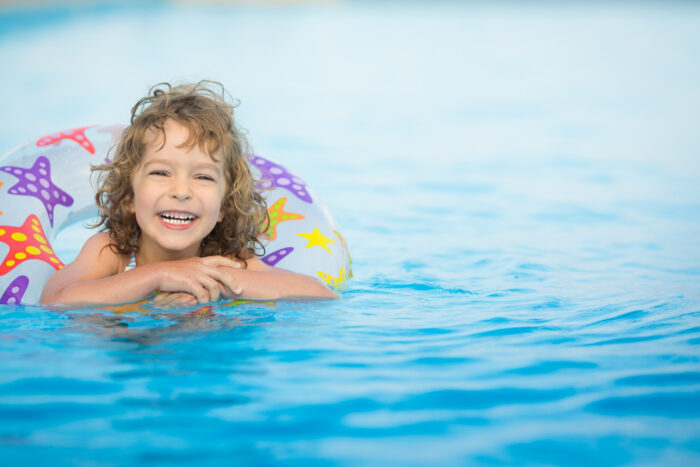 child swimming on pool float toy in water