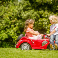 2 year old in a power wheel car outside