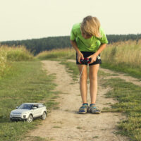 kid playing with a remote control car outside