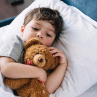 child laying on pillow with teddy bear