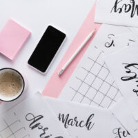 Calendar laying across desk with coffee and pen