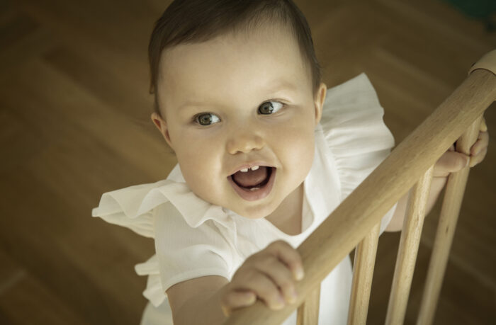 Smiling Girl Standing at Baby Gate