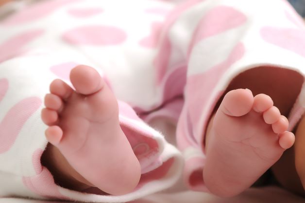 Close up of baby feet sticking out from a pink blanket
