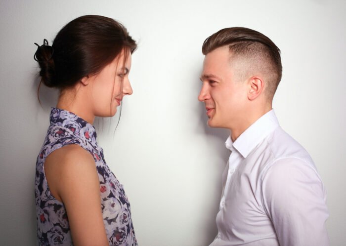 studio shot of young husband and wife talking to each other against white background