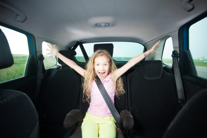 Curly haired girl happy in booster seat in car
