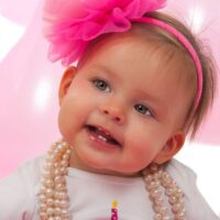 Baby girl dressed up with big pink hair bow and pearls