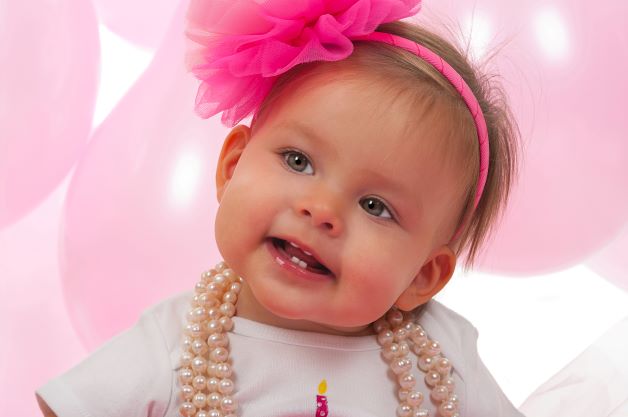 Baby girl dressed up with big pink hair bow and pearls