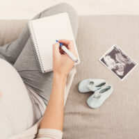 pregnant woman with blank notepad and pen