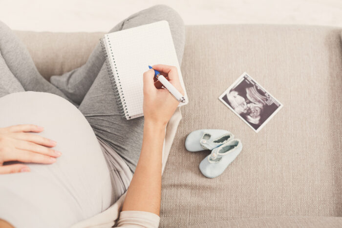 pregnant woman with blank notepad and pen