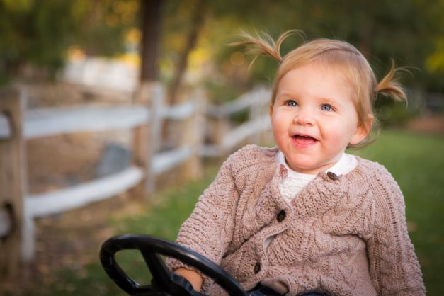 Happy toddler girl in sweater smiling and playing outside