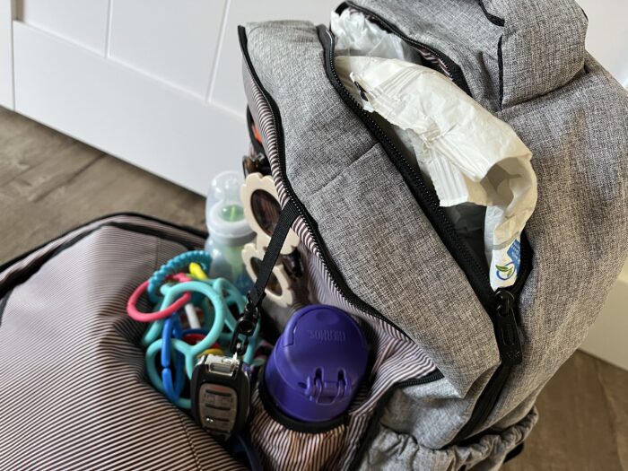 The front main compartment of the HapTim Diaper Backpack unzips almost completely, allowing you to see what's inside.