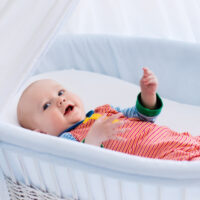 baby laying in a white bassinet
