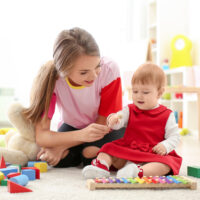 cute baby girl playing with babysitter