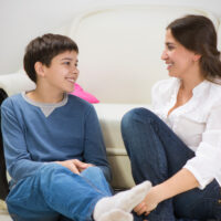 teen boy sitting and talking with his mother