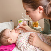 mom getting boogers out of a baby\'s nose