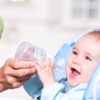 Mother giving water in bottle to baby to keep them hydrated