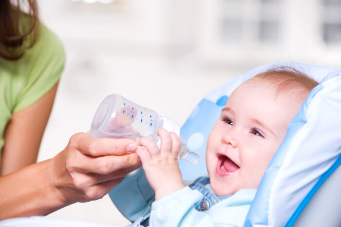 Mother giving water in bottle to baby to keep them hydrated