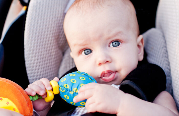 Blue-eyed baby sitting in car seat