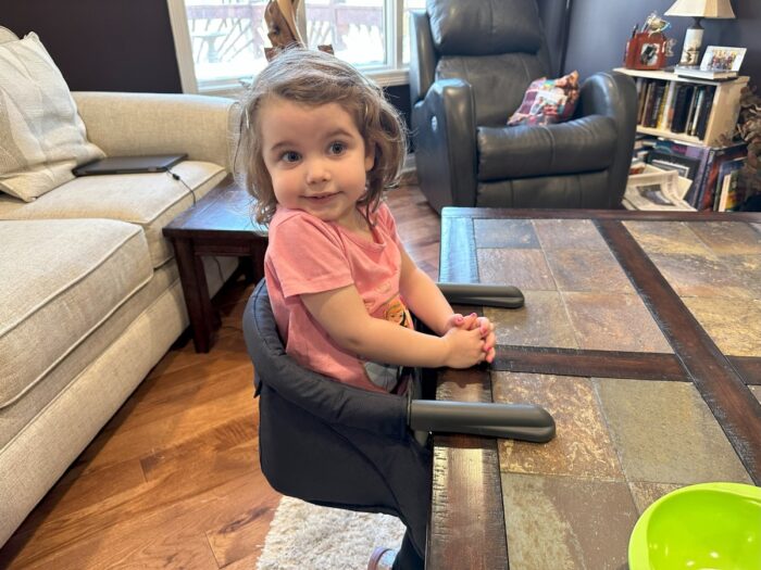 girl in inglesina fast table hook on high chair