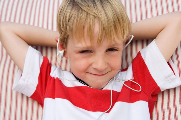 Little boy in red and white shirt listening to ear phones