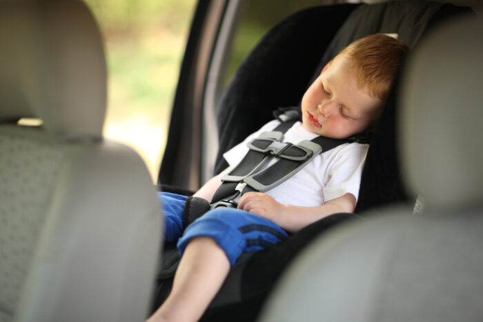 Little blonde boy asleep in car seat