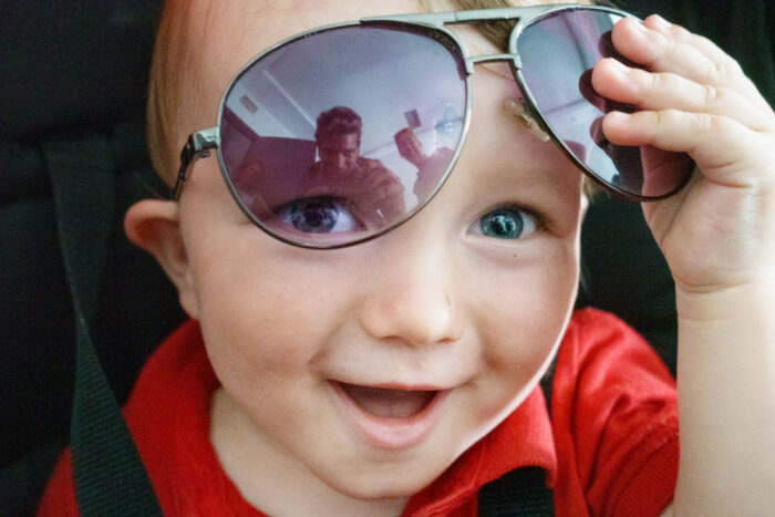 Smiling boy in car seat with sunglasses