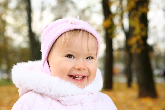 Little toddler girl outdoors in pink hat and coat