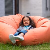 little girl on bean bag chair in the grass