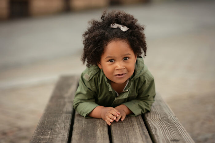 Little Girl Laying on Bench with Curly Hair