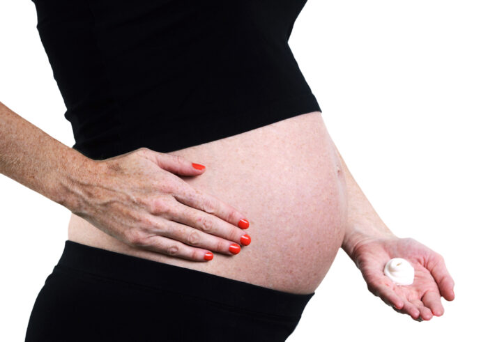 Pregnant woman rubbing cream on stretch marks