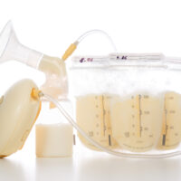 medela breast pump with bags of breastmilk on white background